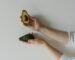 Minimalist image showing hands holding a whole and a sliced avocado, highlighting healthy food.